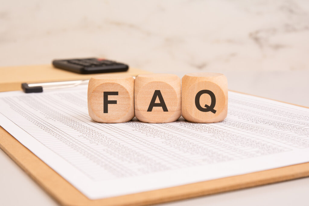 Wooden blocks with FAQ on a financial document. Frequently Asked Questions concept.